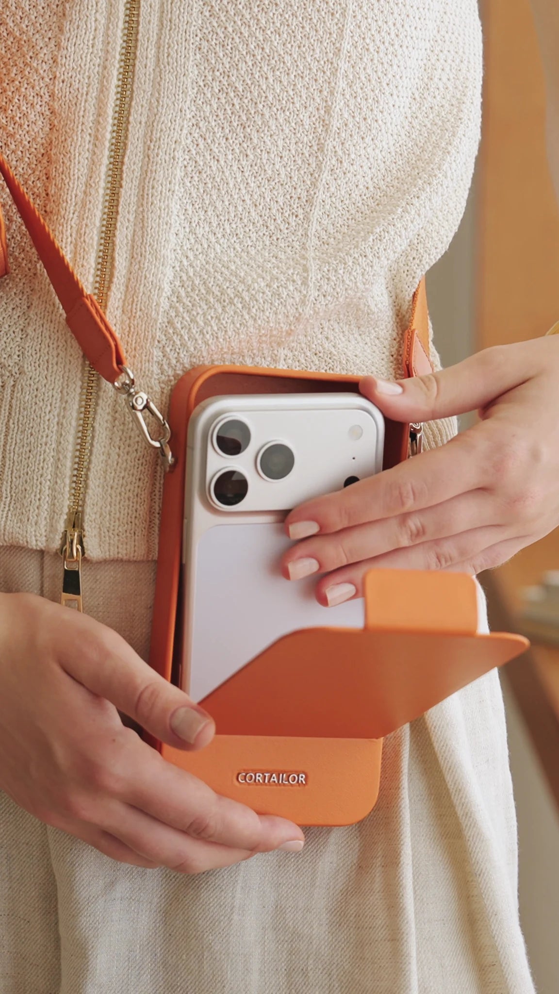 Orange CORTAILOR MagSafe Leather Wallet Stand being placed into a daily carry bag