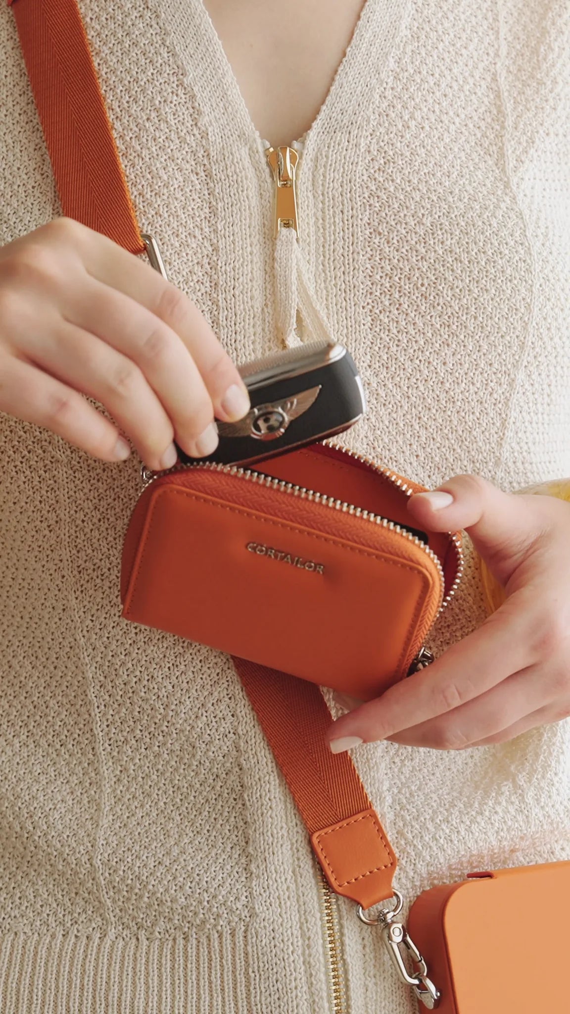 Orange CORTAILOR MagSafe Leather Wallet Stand attached to an iPhone case while a card is being pulled out in a cafe