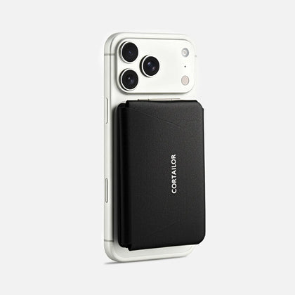 Black MagSafe leather wallet stand attached to a white iPhone, showing the closed front cover and CORTAILOR logo.
