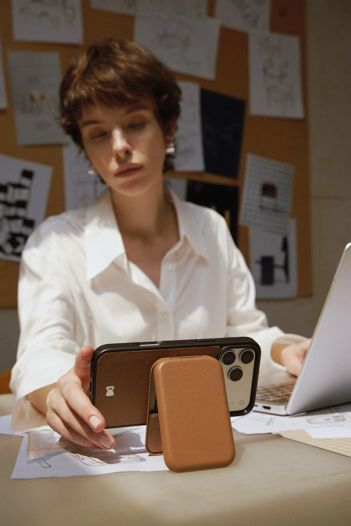 Orange CORTAILOR MagSafe Leather Wallet Stand attached to an iPhone case while a card is being pulled out in a cafe